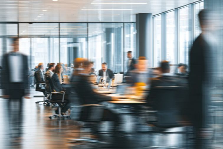 Employees working and moving through a modern, open office environment.